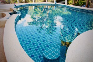 Une piscine dont le bord est revêtu de carreaux et dont la forme est incurvée.