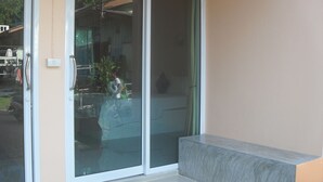 A hotel entrance with a sliding glass door, a welcome mat, and a bench outside. - Budchui Village 2 (Koh Tao)