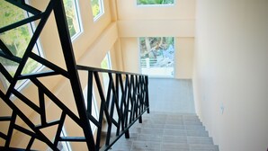 A staircase with a geometric metal railing leading to an outdoor area with trees and a fence. - Budchui Village 2 (Koh Tao)