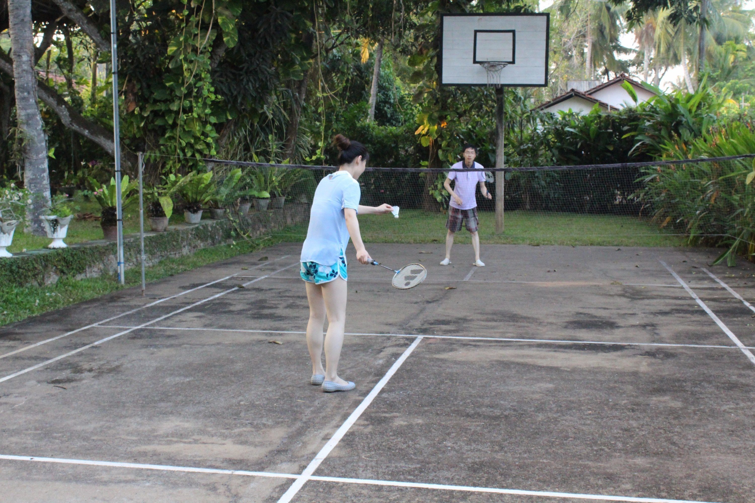 Een tennisbaan met een net, omgeven door groen.