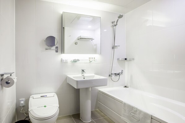 A modern bathroom with a toilet, sink, mirror, and shower.