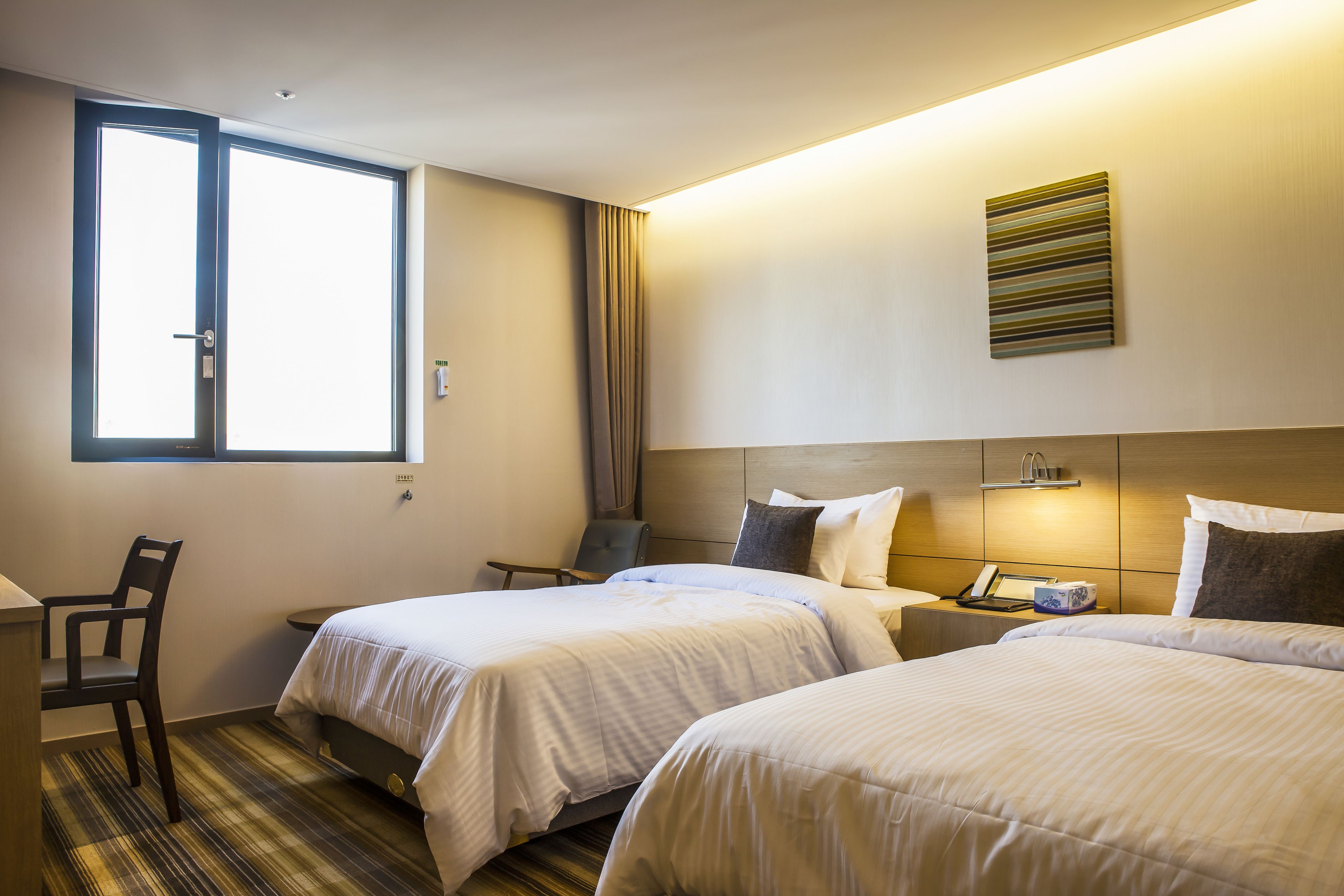 Una habitación de hotel con dos camas, un escritorio, una silla y una ventana.