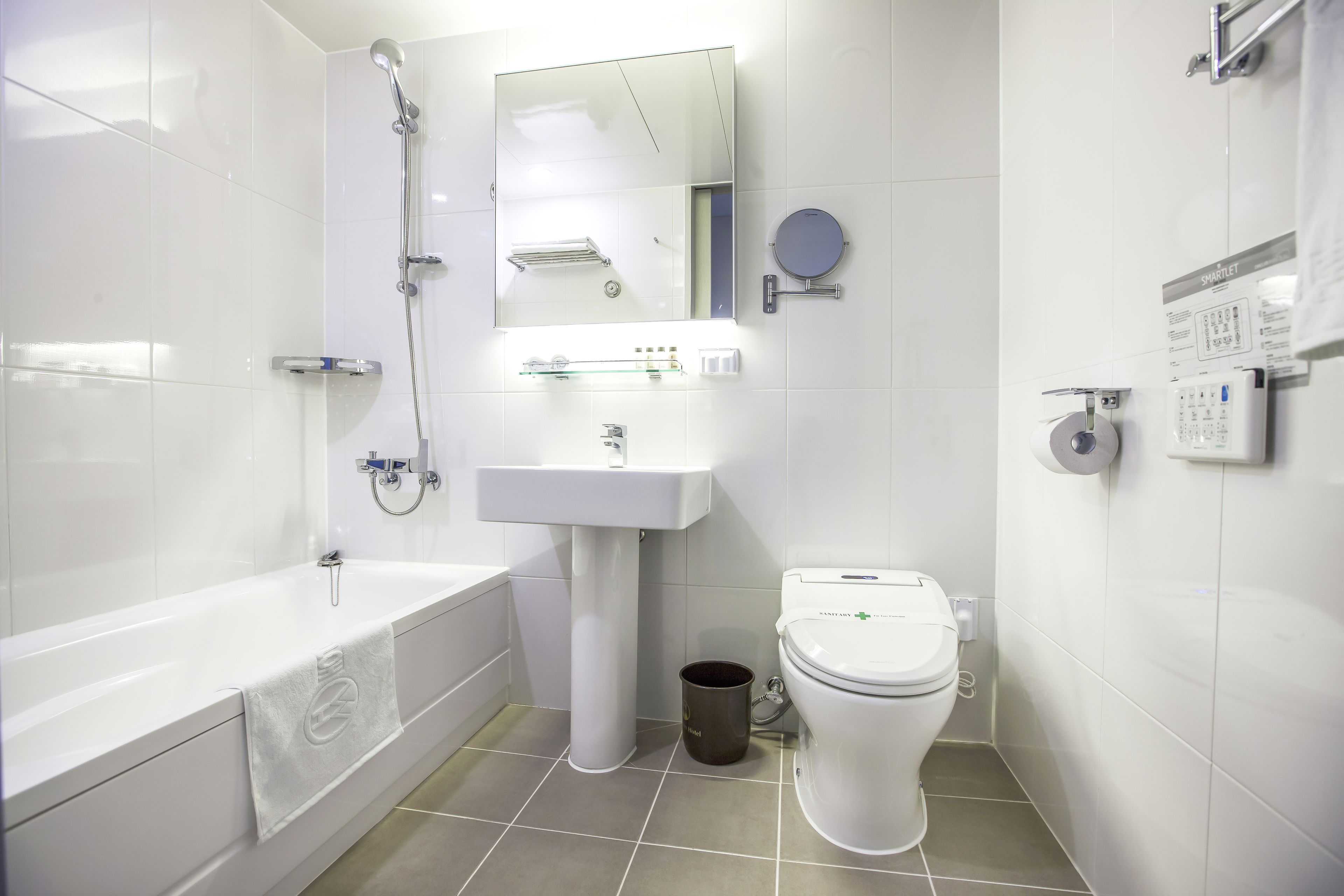 A modern bathroom with a bathtub, sink, toilet, and a mirror.