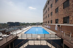 Una piscina en la azotea con sillones de descanso y vistas del horizonte urbano.