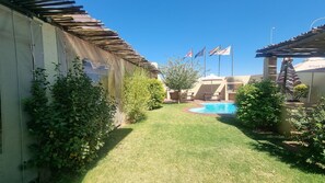 A backyard with a swimming pool, a pergola, and flags. - Kathu Inn by Country Hotels (Kathu)
