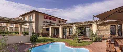 A pool area with a sign for Kathu Inn by Country Hotels.