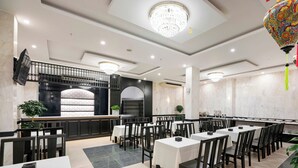 Un restaurant doté de plusieurs tables et chaises, d’un comptoir et d’un luminaire décoratif au plafond.