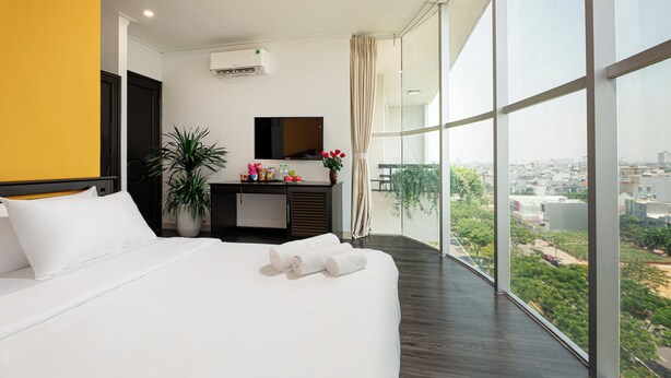 Une chambre d’hôtel moderne avec un grand lit, un bureau avec un miroir et une vue sur la ville.
