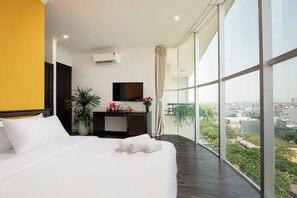 A modern hotel room with a large bed, a desk with a mirror, and a view of the city. - Amanda Boutique Hotel (Da Nang)