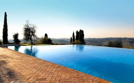 Una piscina al aire libre, sombrillas, sillones reclinables de piscina