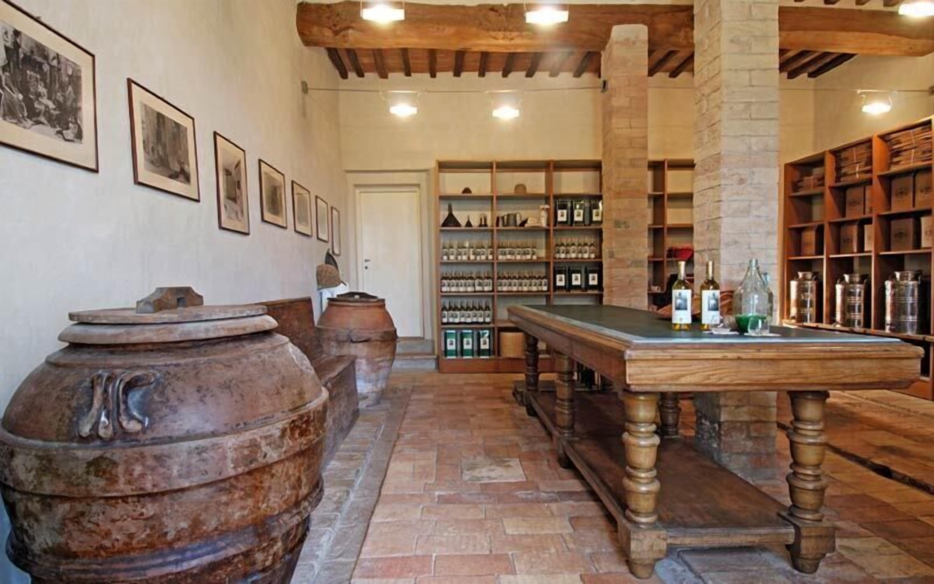 A rustic interior with wooden barrels, a long table, and shelves of wine bottles.