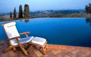 Una piscina al aire libre, sombrillas, sillones reclinables de piscina