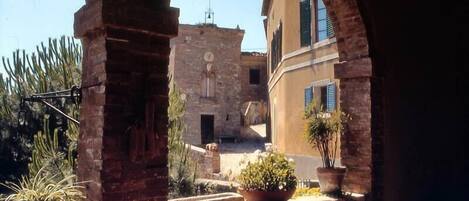 A courtyard with a stone wall, potted plants, and a building with a clock tower.