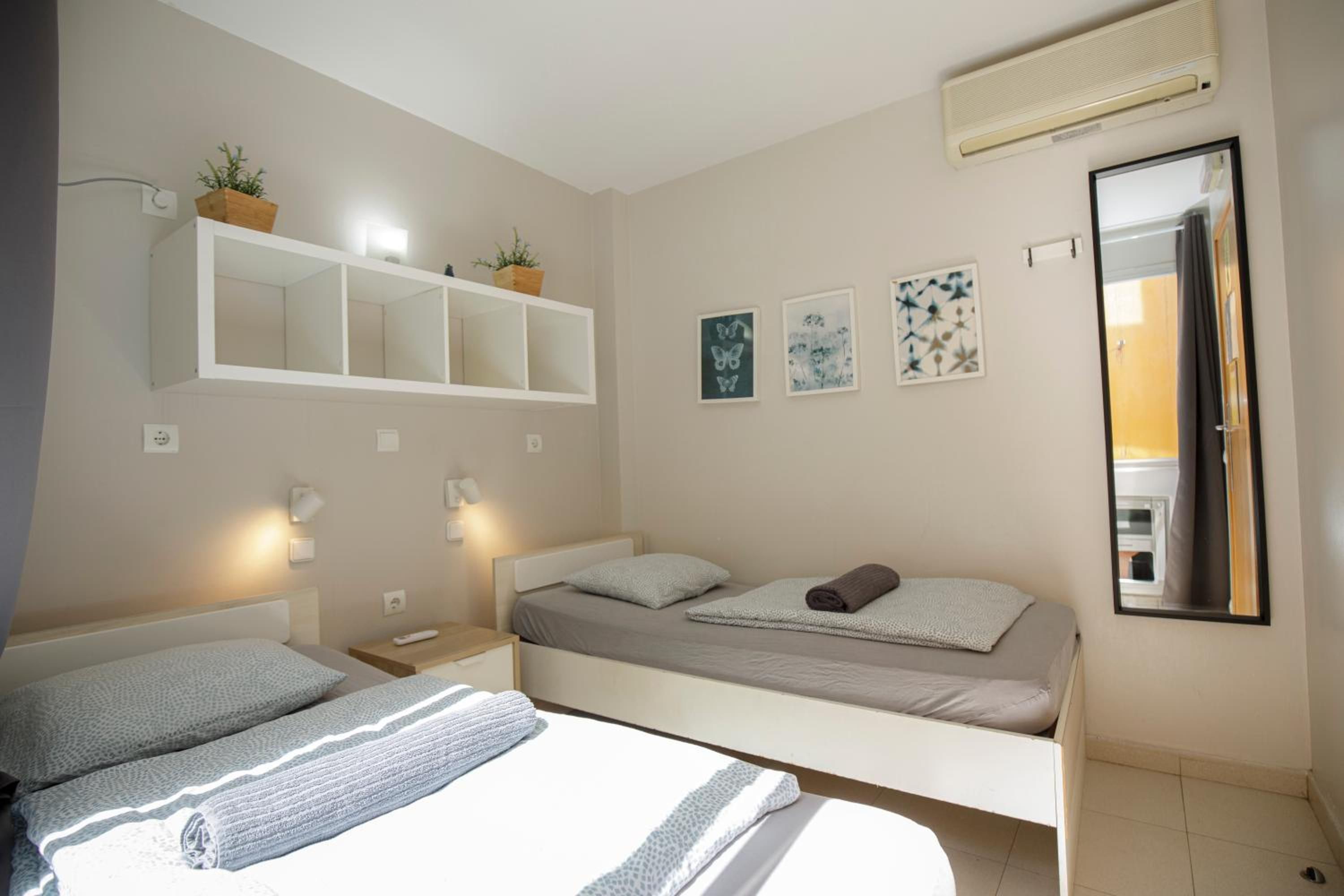 Une chambre à coucher comprenant un lit, des tables de chevet, des étagères murales et un miroir.