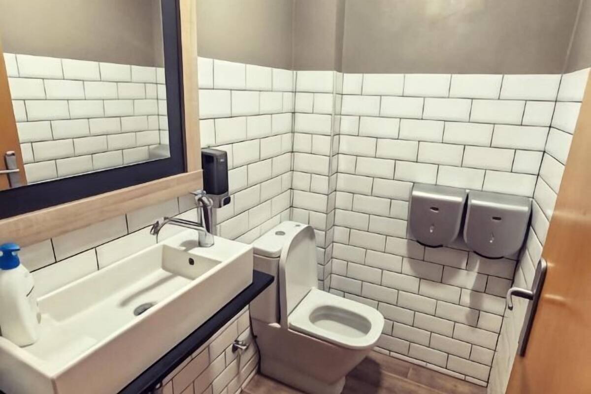 Casa de banho com lavatório, sanita e dispensadores de sabonete líquido.