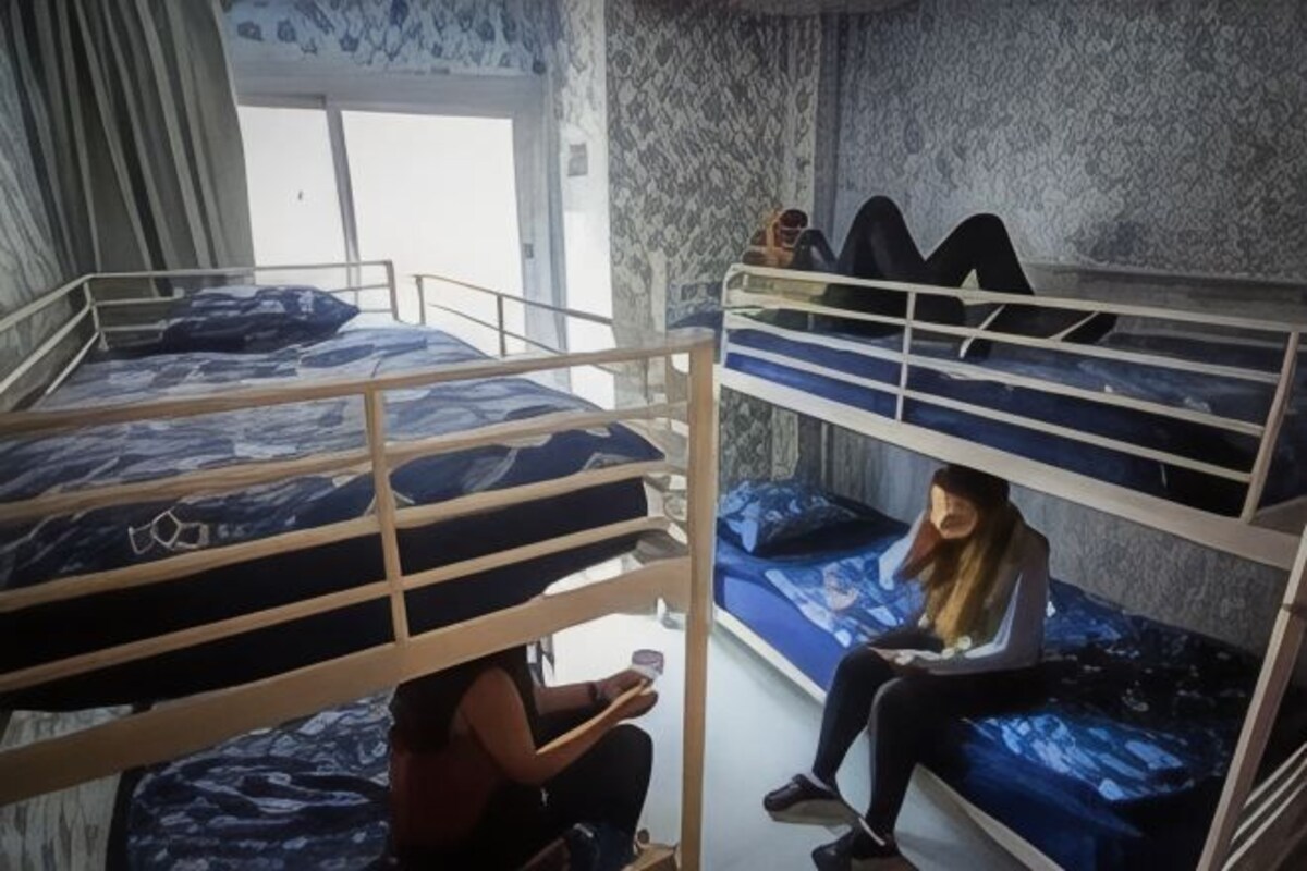 A dormitory room with bunk beds, a window, and a patterned wall.