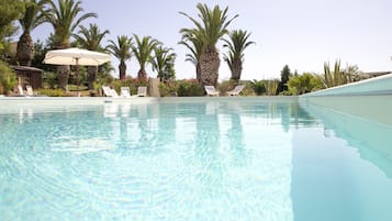 Una piscina al aire libre de temporada, sombrillas