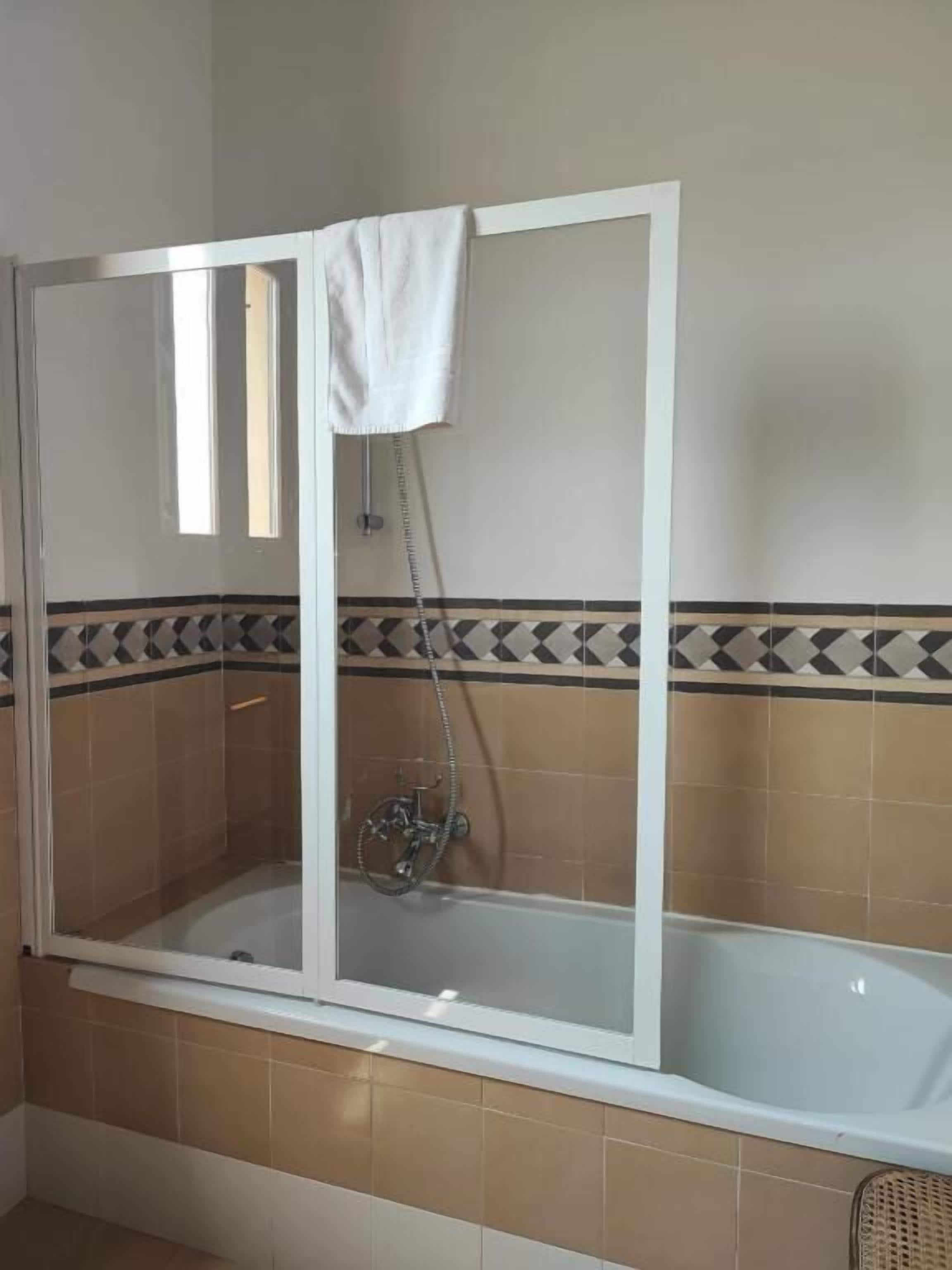 A bathroom with a glass-enclosed shower, a bathtub, and a tiled floor.