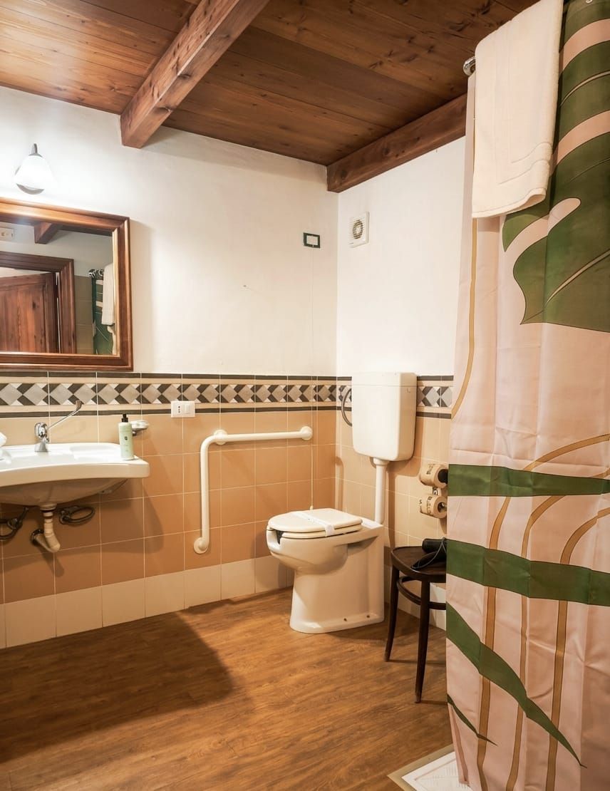 A bathroom with a wooden ceiling, a sink, a toilet, and a shower curtain.
