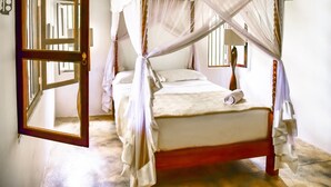 A four-poster canopy bed with a white bedspread and a rolled towel on the footboard. - Dansala Cottage (Koggala)
