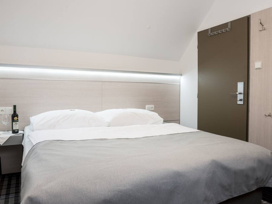 A hotel room with a bed, bedside table, and a wardrobe.