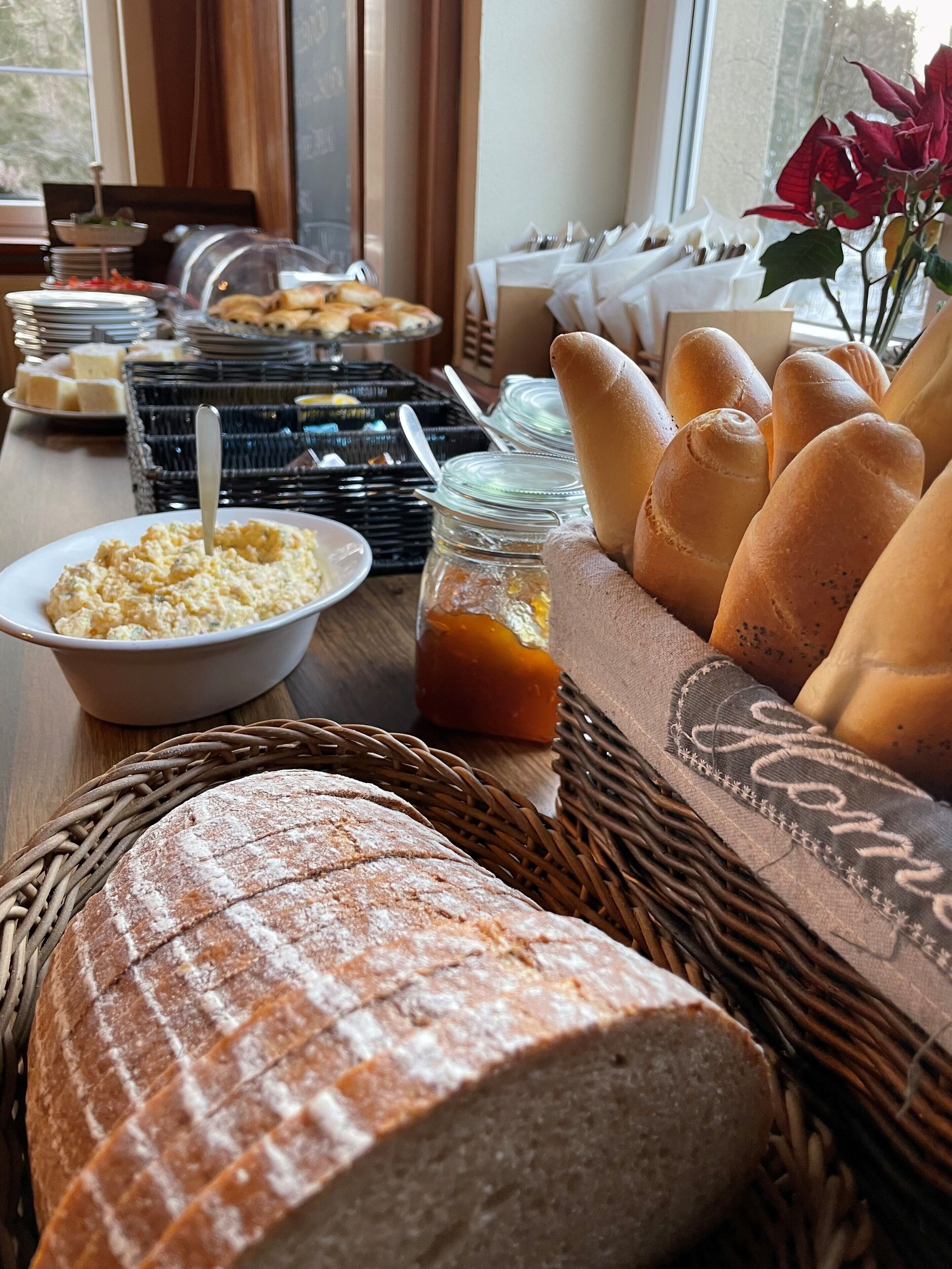 Una mesa de buffet con diversos alimentos, como pan, pasteles y salsas.