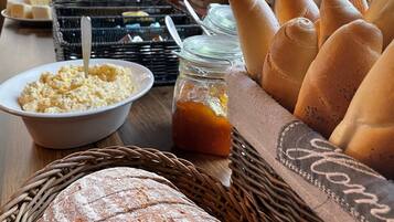 Una mesa de buffet con diversos alimentos, como pan, pasteles y salsas.