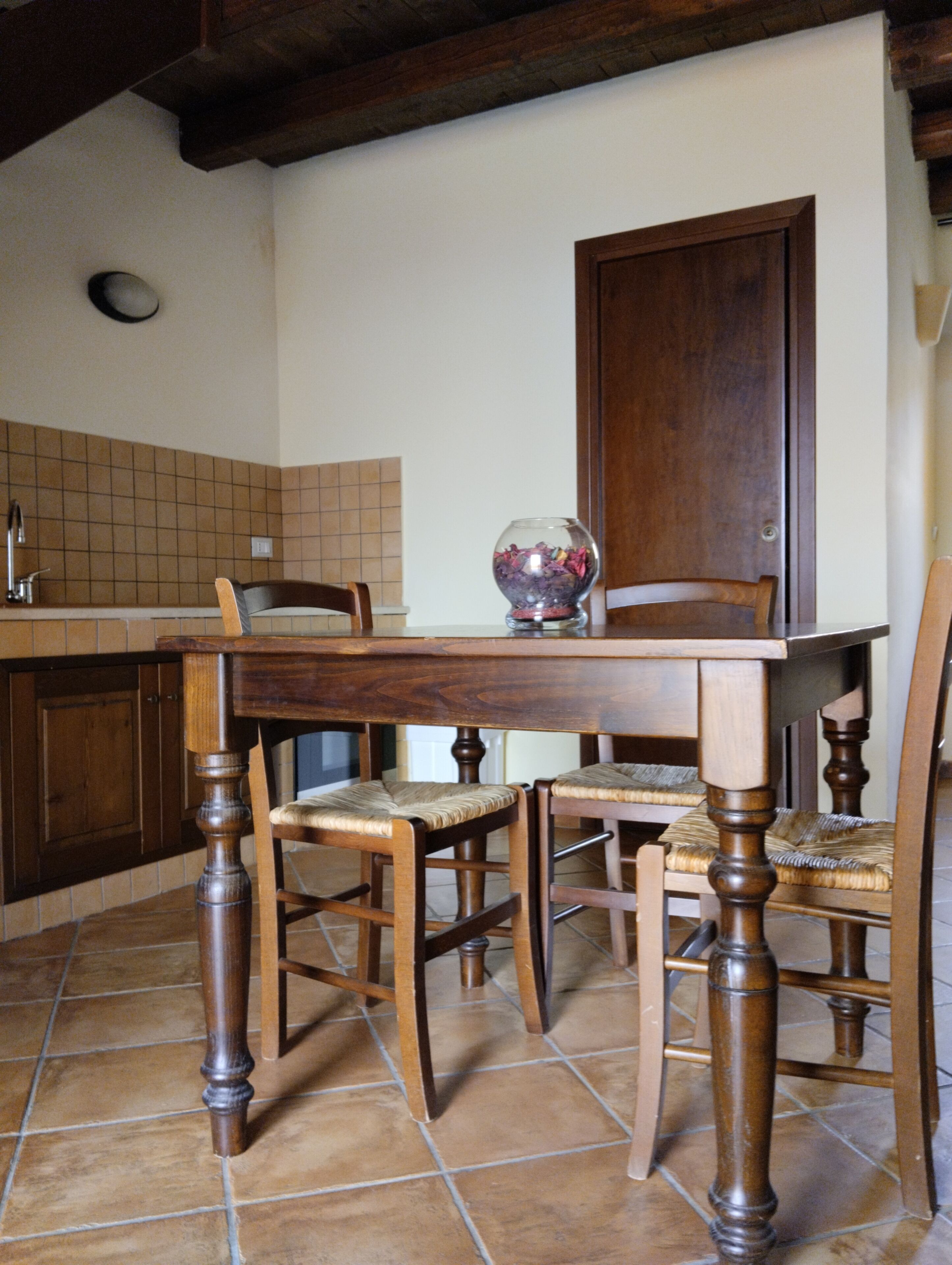 A kitchen with wooden furniture, a tiled backsplash, and a door.