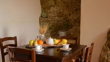 A wooden dining table with chairs, a fruit bowl, a teapot, and cups.