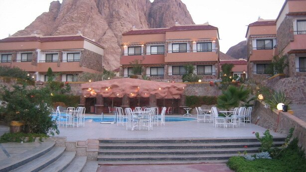 Un hôtel doté d'une piscine, d'un espace extérieur aménagé et offrant une vue sur les montagnes.