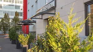 A reception area with a sign, potted plants, and a red pillar. - Goethe Conference Hotel by Trip Inn (Frankfurt)