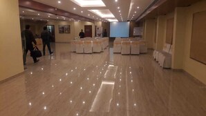 Une salle de conférence spacieuse, dotée d’un sol ciré, de rangées de chaises et d’un écran de présentation.