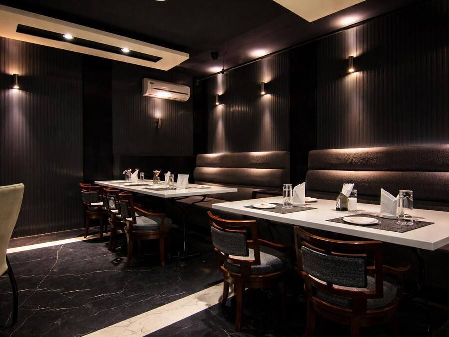 A restaurant with booth seating, rectangular tables, and a dark interior.