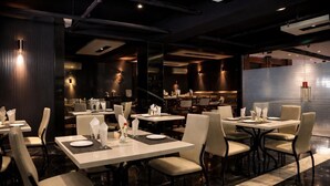 Un restaurant moderne doté de nombreuses tables et chaises, d’un sol en marbre et d’un éclairage contemporain.