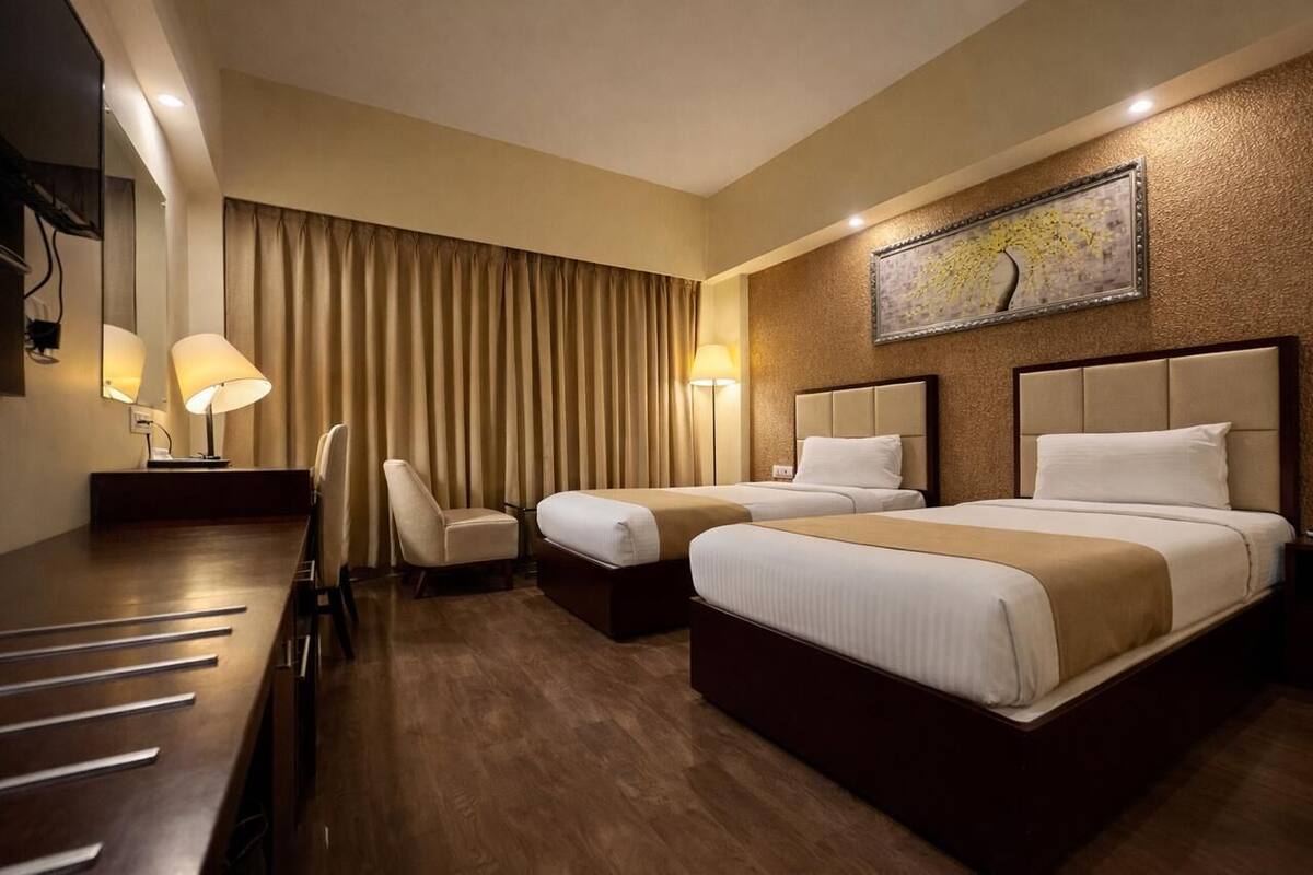 A hotel room with two beds, a desk, and a chair.