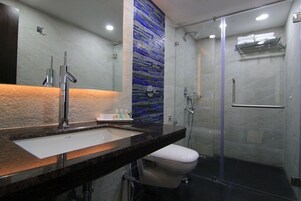 Un baño moderno con encimera de mármol, inodoro blanco, cabina de ducha de vidrio y pared con mosaico azul.