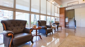 A lobby with large windows, leather armchairs, a small round table, and a wooden chair. - Hualien Lohas Hotel (Hualien City)