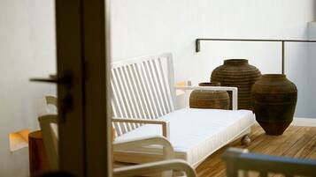 Un dormitorio con una cama blanca, una silla blanca y dos jarrones grandes sobre un suelo de madera.