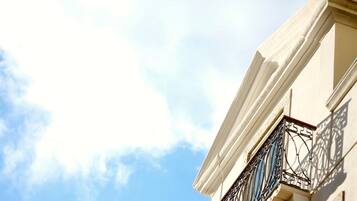 A building corner with a clear sky and a decorative metal balcony.