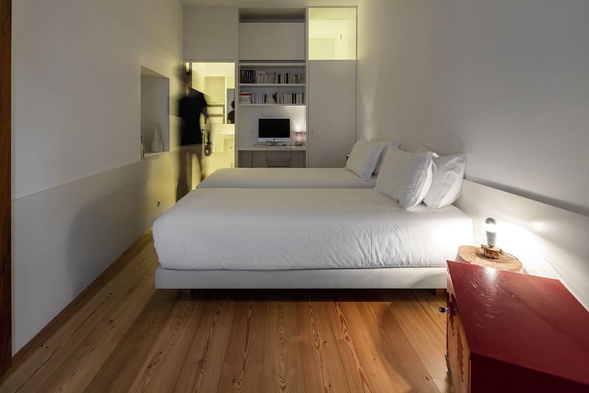 A bedroom with a bed, a bedside table, a red chair, a TV, and a bookshelf.