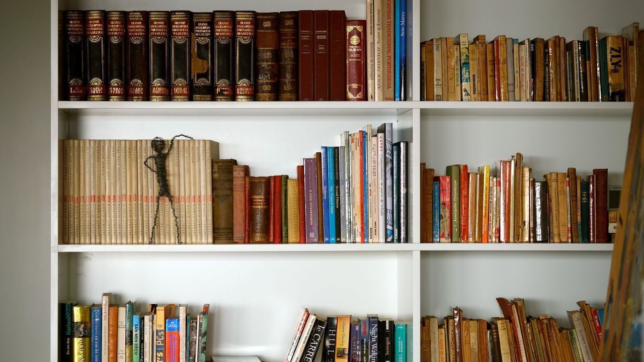Una estantería con varios libros, algunos con la lomo hacia afuera y otros con la encuadernación hacia adentro.