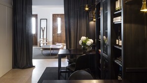 A modern dining area with a dark wooden table and chairs, a vase of white flowers, and a wine rack with bottles.