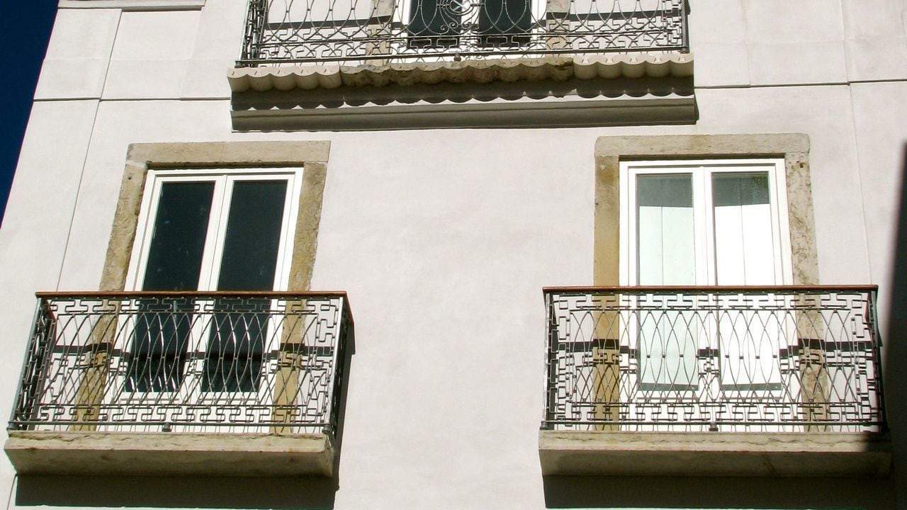 A building facade with three windows and two balconies.