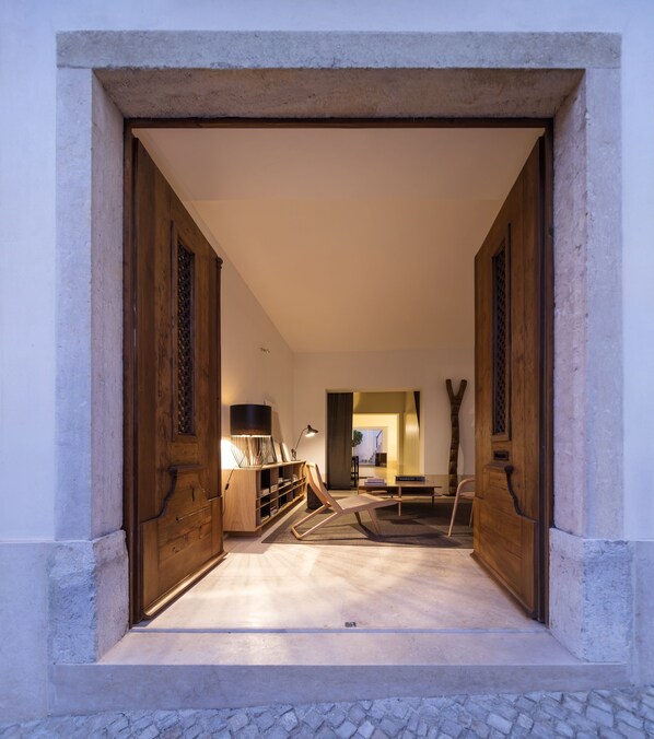 A hallway with a wooden door frame, a bookshelf, and a seating area with a chair and a table.