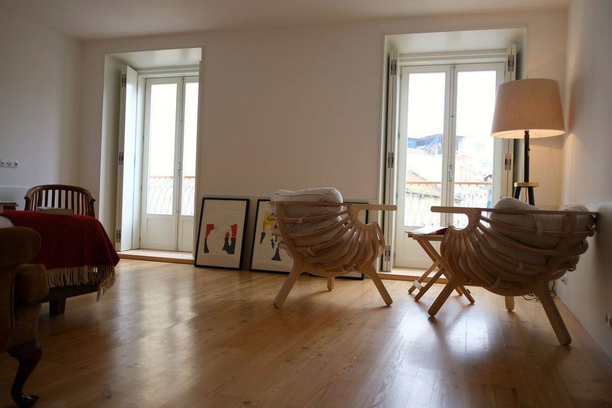 A spacious room with wooden flooring, two wooden chairs, a table, and a lamp.