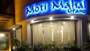 Un hôtel appelé « Moti Mahal Grand », doté d’une façade incurvée et d’une enseigne lumineuse.