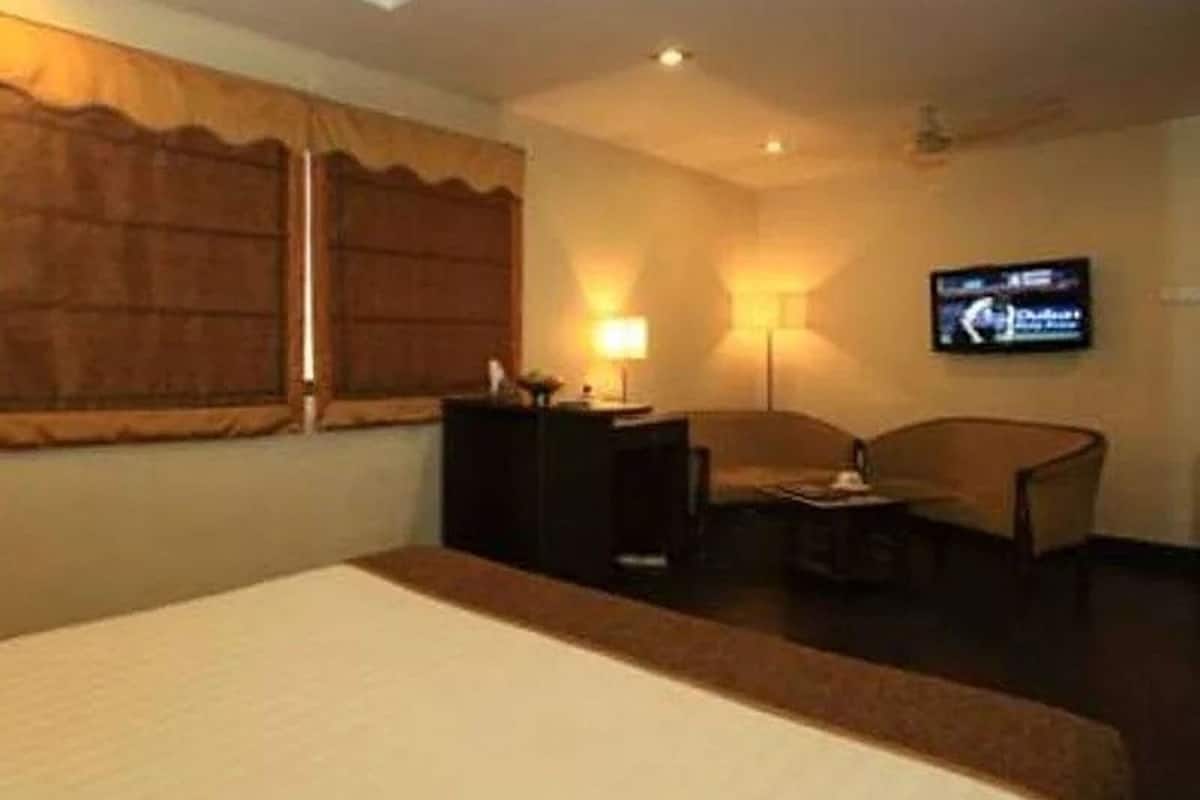 A hotel room with a bed, a desk, a chair, a television, and a window with curtains.