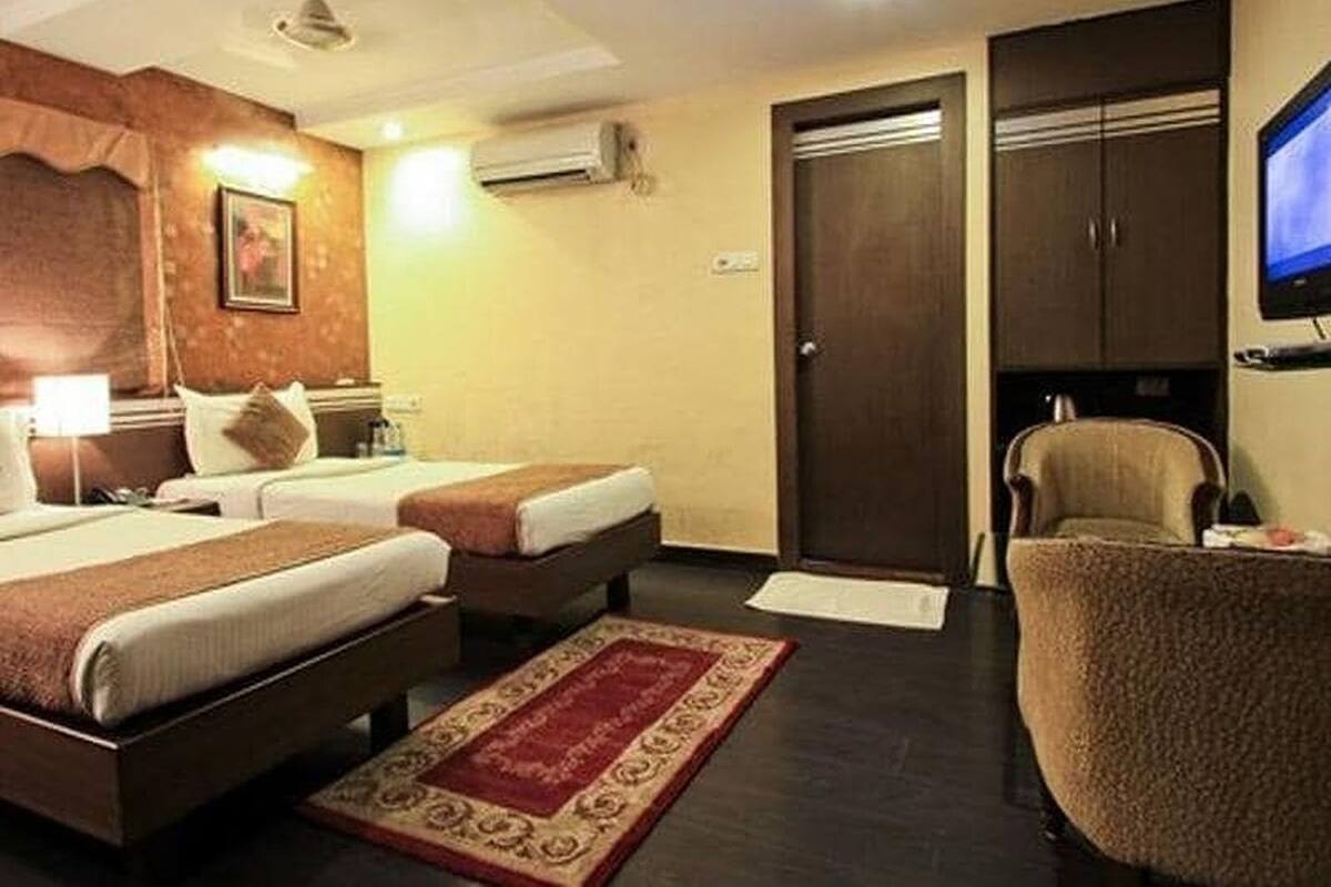 A hotel room with two beds, a TV, a desk, and a chair.