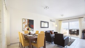 Ein modernes Wohnzimmer mit Essbereich, einer Couch und einem Balkon mit Tisch und Stühlen.