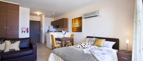 Un dormitorio moderno con cama, mesita de noche y pequeño espacio de escritorio.